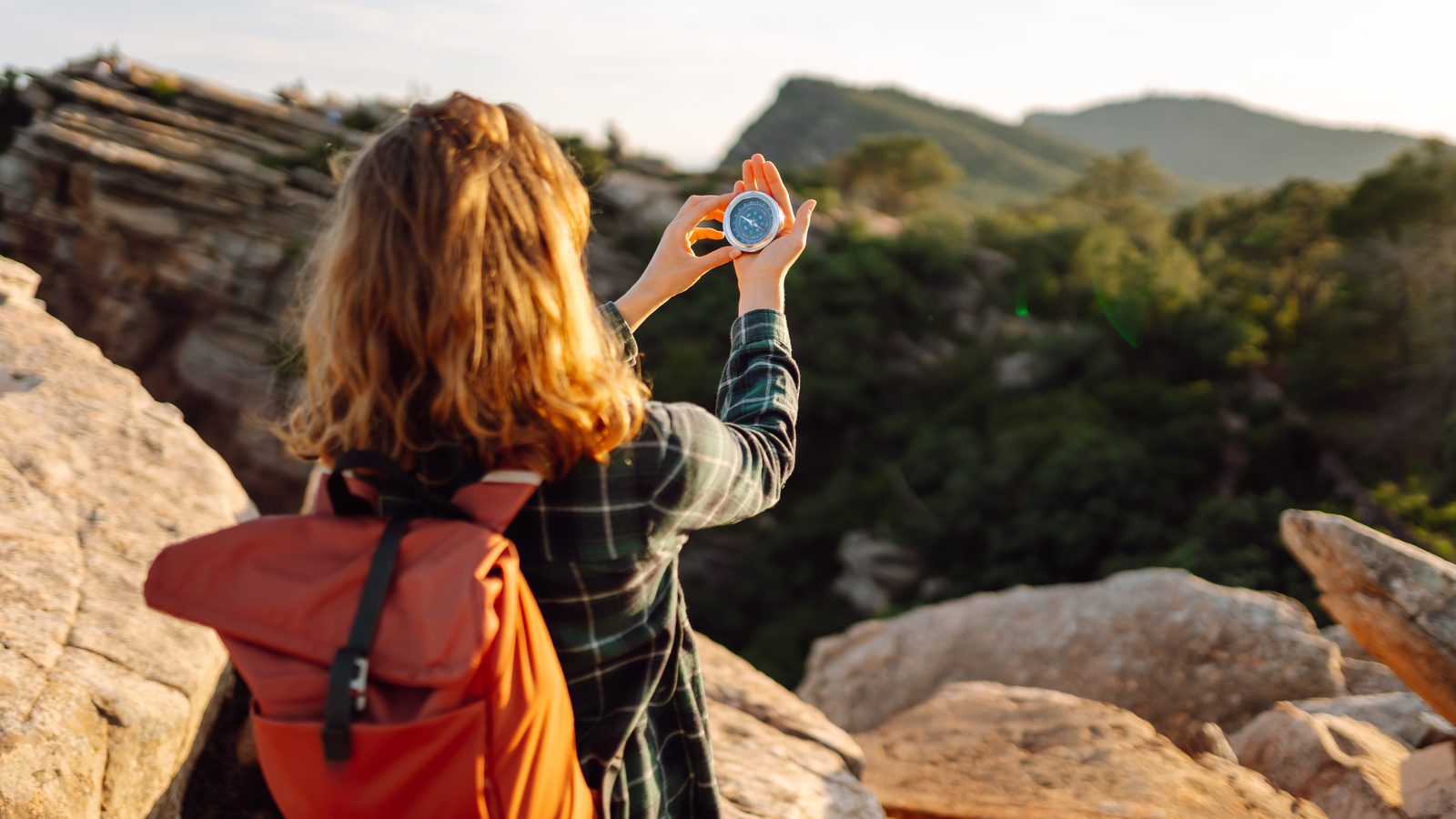 A walker with a rucksack taking a bearing with a compass