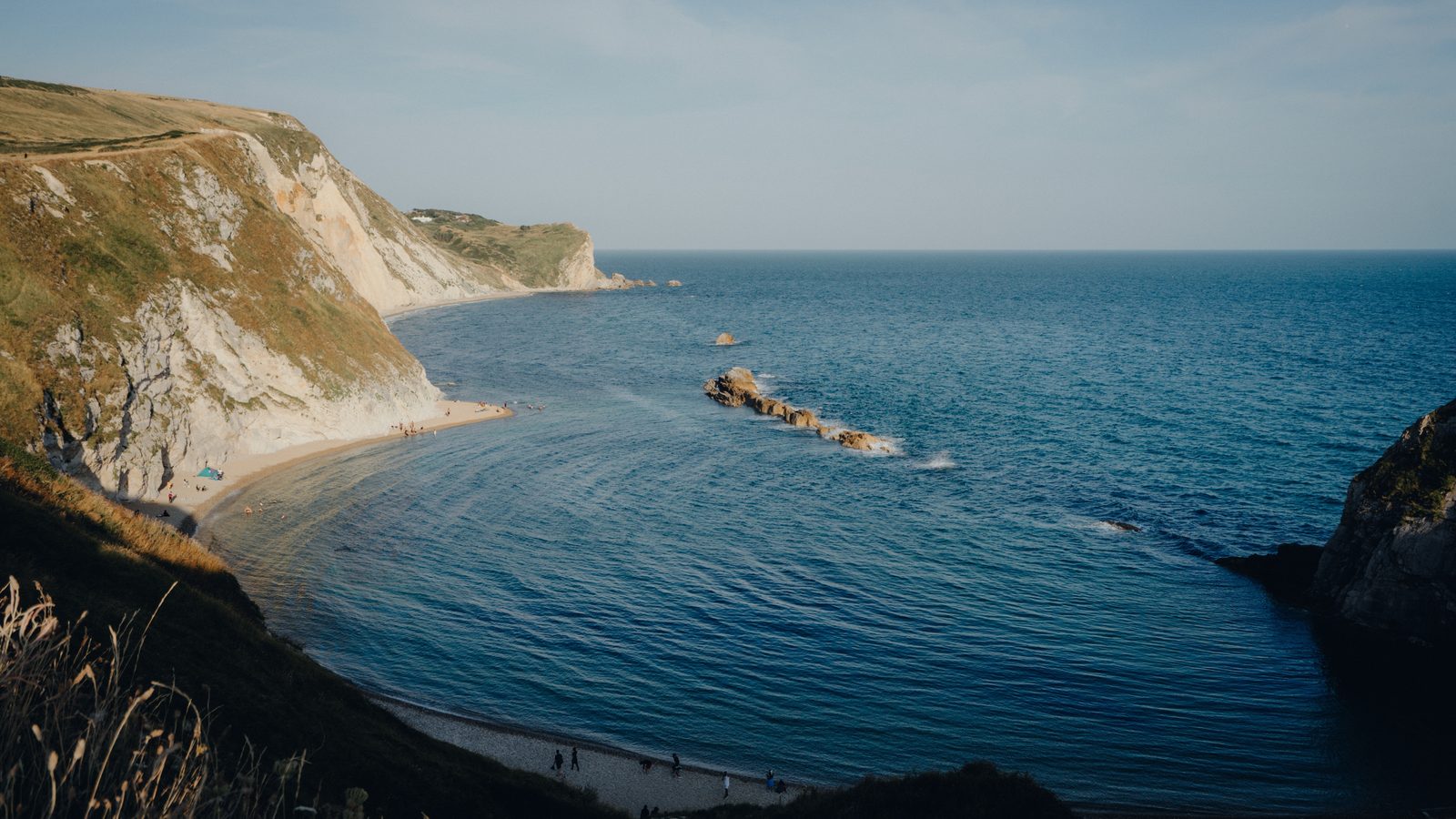 Chalk cliffs and a shingle bay in late-afternoon light on the Ferrybridge to Lulworth Cove stage in Dorset